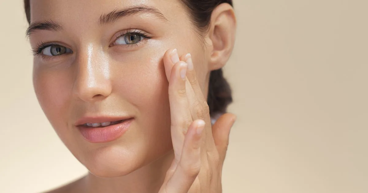Close-up of a mature woman with smoother, firmer skin touching her face, showing the results of the Tribella facial.